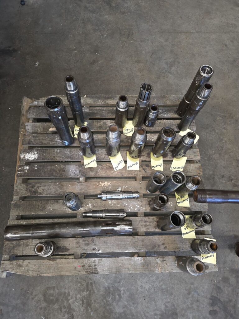 Drilling subs laid out on a pallet for thread inspection